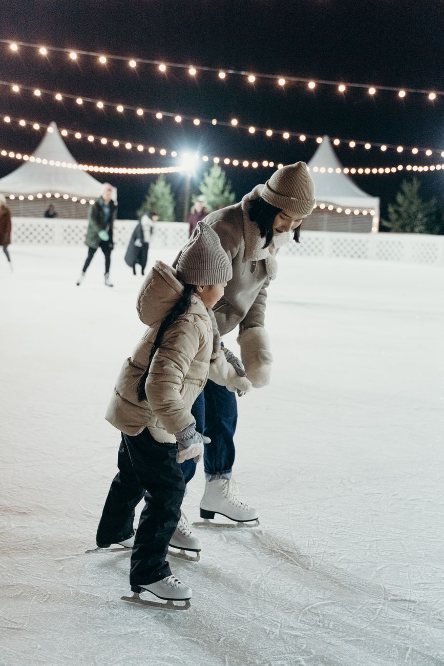 woman and a child wearing beanies ice skating